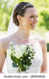 Happy young bride with flower bouquet in garden