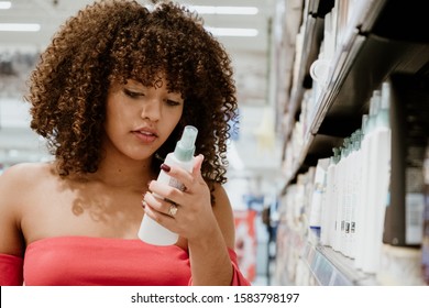 Happy Young Brunette With Curly Hair Buying Shampoo In Supermarket