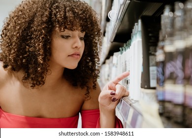 Happy Young Brunette With Curly Hair Buying Shampoo In Supermarket