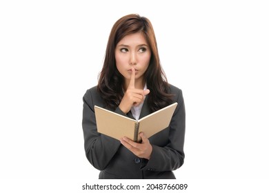 Happy young business Asian woman making a shushing gesture holding her index finger to her lips as she asks for quiet with book,silence or secrecy for a surprise,isolated on white background