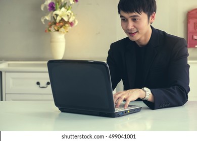 Happy Young Business Man, Smiling, As He Works On His Laptop To Get All His Business Done Early In The Good Work