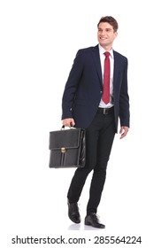 Happy Young Business Man Walking With A Briefcase In His Hand While Looking Away From The Camera.