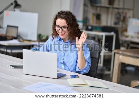 Happy young business woman employee, hr manager having remote online work hybrid meeting or distance job interview waving hand looking at laptop during virtual video conference call in office.