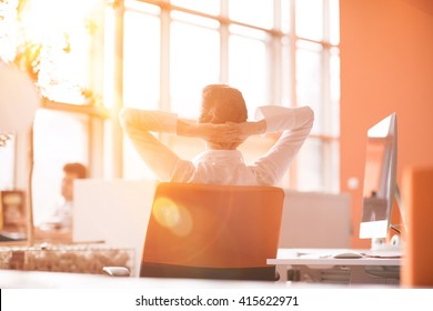 Happy young business woman relaxing and geting insiration while working on desktop computer at modern bright  starup office interior. Morning sunrise or sunset with sun flare in background. - Powered by Shutterstock