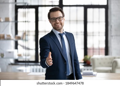 Happy young businessman in glasses looking at camera, reaching out hand making welcoming gesture or ready handshaking with partner or colleague, smiling banker proposing good deal to client. - Powered by Shutterstock