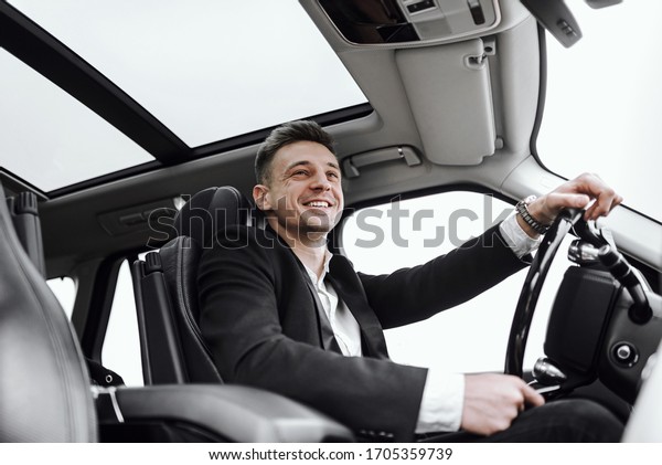 Happy young businessman having test drive new\
car. Rent and trade-in\
concept