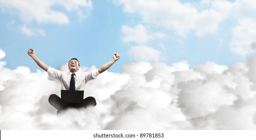 Happy Young Businessman With Laptop Sitting On The Clouds.