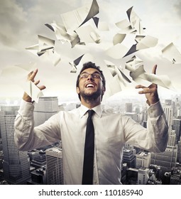 Happy Young Businessman Throwing Paper Sheets In The Air With Cityscape In The Background