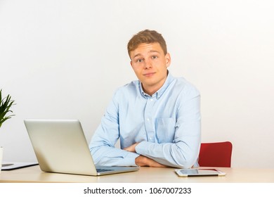 Happy Young Businessman Using Laptop At His Office Desk And Smiling, Look Straight Ahead.