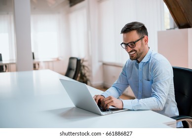 Happy young businessman using laptop at his office desk. - Shutterstock ID 661886827