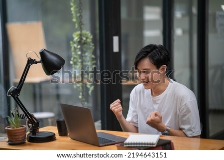 Happy young businessman works on laptop computer finish with excited and success on a desk at home, businessman using a notebook with achievement and surprise, freelance or employee, 