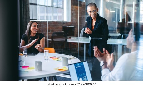 Happy young businesswoman being applauded by her colleagues during a meeting in a modern office. Successful young businesswoman smiling cheerfully while receiving praise from her colleagues. - Shutterstock ID 2127480077
