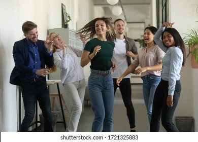 Happy young businesswoman and businessman dancing after successful deal. Diverse smiling employee energy moving for break and relaxing. Overjoyed motivated carefree multiracial business team. - Shutterstock ID 1721325883