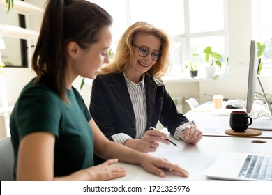 Happy Young Businesswoman Presentation Project Using Laptop For Mature Female Mentor In Boardroom At Meeting. Smiling Leader Presenting New Business Concept For Woman Colleague Discuss.