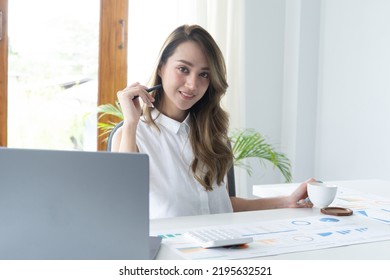 Happy Young Businesswoman Using Calculator At Workplace