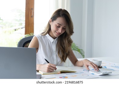 Happy Young Businesswoman Using Calculator At Workplace