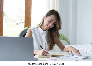 Happy Young Businesswoman Using Calculator At Workplace