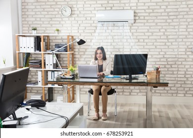 Happy Young Businesswoman Working In Office With Air Conditioning