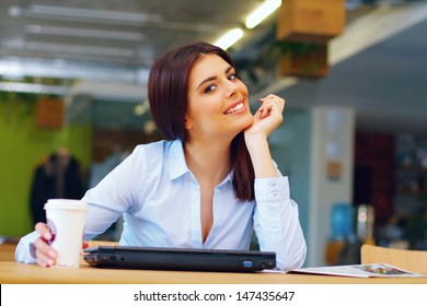 Happy Young Busineswoman Sitting In The Office With Laptop And Coffee