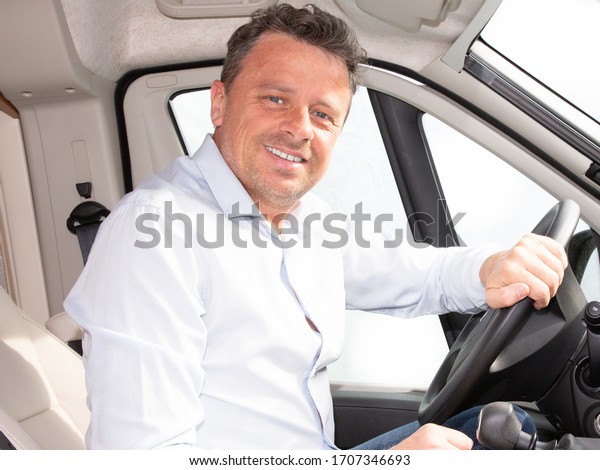 Happy young car driver behind steering wheel of\
van driving concept