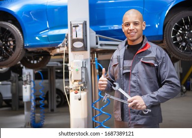 Happy Young Car Technician Showing Thumbs Up While Repairing A Car At The Workshop