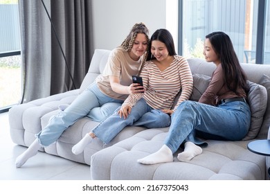 Happy young carefree diversity women friends in casual using phone, having fun together at home - Shutterstock ID 2167375043
