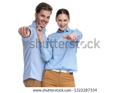 happy young casual couple pointing fingers together on white background