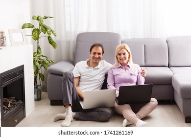 Glückliches junges, lässiges Ehepaar, das im Büro zu Hause zusammenarbeitet und lächelt.