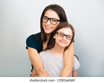 Happy Young Casual Mother And Smiling Kid In Fashion Glasses Hugging On Light Blue Background With Empty Copy Space. Closeup Studio Portrait