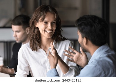 Happy young Caucasian businesswoman enjoying professional discussion with Indian coworker man, listening, smiling, laughing. Two diverse colleagues talking, chatting at meeting table - Powered by Shutterstock