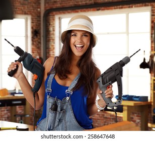 Happy Young Caucasian Casual Woman Holding Power Drill At Workshop. Smiling, Looking At Camera, Standing.