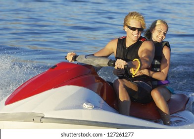 Happy Young Caucasian Couple Riding Jet Ski On Lake