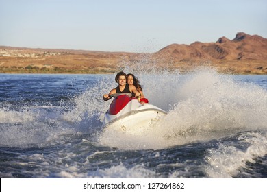 Happy Young Caucasian Couple Riding Jet Ski In Speed On Lake