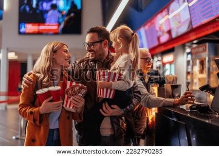 A happy young Caucasian family is at the cinema hall, shopping for tickets, popcorn and beverages before seeing a movie. Foto stock © 