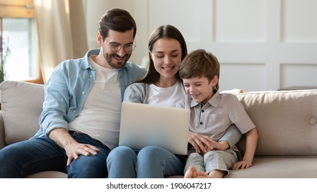 Happy young Caucasian family with little son relax on sofa at home talk on video call on laptop. Smiling parents with small 7s boy child look at computer screen watch funny cartoon online on gadget. - Powered by Shutterstock