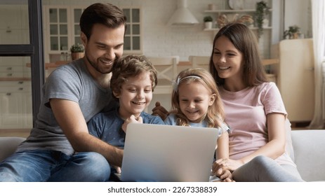 Happy young caucasian family with small children relax on sofa in kitchen have fun using laptop together, smiling parents rest on couch enjoy domestic weekend with little kids watch video on computer - Powered by Shutterstock