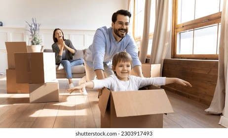 Happy young Caucasian family with small son have fun on relocation day to new house or apartment. Smiling man and woman enjoy unpacking with little child moving to own home. Rent, mortgage concept. - Powered by Shutterstock