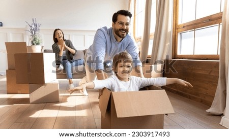 Happy young Caucasian family with small son have fun on relocation day to new house or apartment. Smiling man and woman enjoy unpacking with little child moving to own home. Rent, mortgage concept.