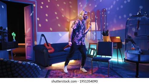 Happy Young Caucasian Handsome Stylish Man Listening To Music In Headphones And Dancing Making Rhythmic Moves In Living Room In Disco Ball Light In Apartment, Retro Style, Having Fun, Leisure Concept