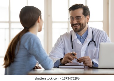 Happy Young Caucasian Male GP Or Physician In White Medical Uniform Have Consultation With Female Patient In Private Hospital. Smiling Man Doctor Consult Woman Client At Meeting In Clinic.