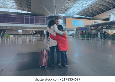 Happy young Caucasian man, his wife and children greeting and embracing each other after long separation at international airport building. Long-awaited family reuniting - Powered by Shutterstock