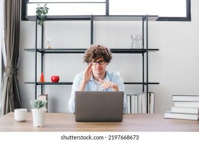 Happy Young Caucasian Man Wearing Glasses And Smiling Working Typing On His Laptop To Get All His Business Done Early In The Morning With His Cup Of Coffee. Young White Man Studying Online At Home.