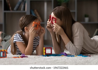 Happy young Caucasian mother and cute small teenage daughter have fun play together with colorful blocks at home. Smiling mom and little girl child laugh involved in creative playful game activity.