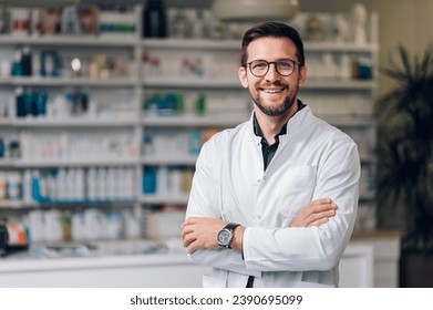 A happy young Caucasian pharmacy shop owner, standing in their newly-opened pharmacy shop. Wearing a white coat, glasses and a watch. The stature reflects success and high hopes for their business. - Powered by Shutterstock