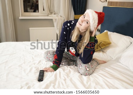 Happy young Caucasian pretty girl wearing Santa sweater and enjoys in the bedroom alone