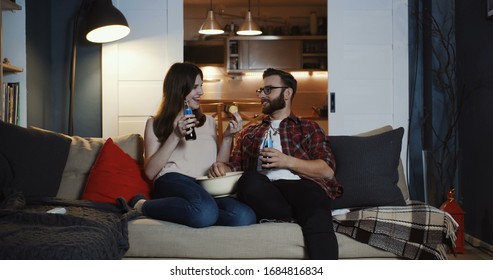 Happy Young Caucasian Romantic Couple Sit Together For A Relaxed Movie Night At Home With Snacks And Drinks Slow Motion.