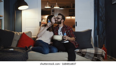 Happy Young Caucasian Romantic Couple Sit Together For A Relaxed Movie Night At Home With Snacks And Drinks Slow Motion.