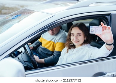 Happy young caucasian woman driving her new car holding car license. - Powered by Shutterstock