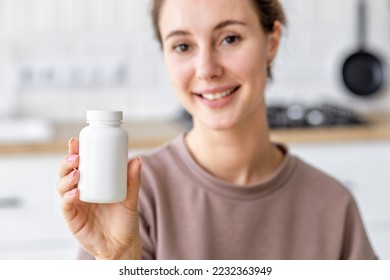 Happy young caucasian woman holding bottle of dietary supplements or vitamins in her hands. Close up. Healthy lifestyle concept - Powered by Shutterstock