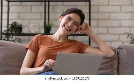 Happy Young Caucasian Woman Relaxing On Couch With Computer On Laps, Having Fun Watching Comedian Movie Or Video, Entertaining Shopping Alone At Home, Enjoying Free Weekend Leisure Time Online.